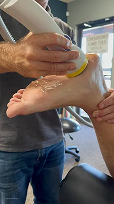 A patient receiving softwave therapy on their foot